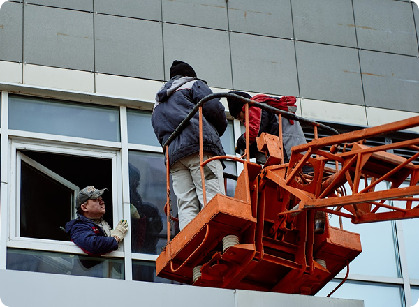 Installation crew working from a lift on a commercial building window