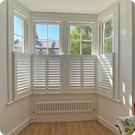 White cafe shutters installed across a bay window