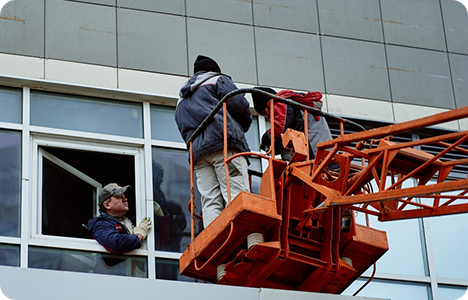 Installation crew working from a lift on a commercial building window